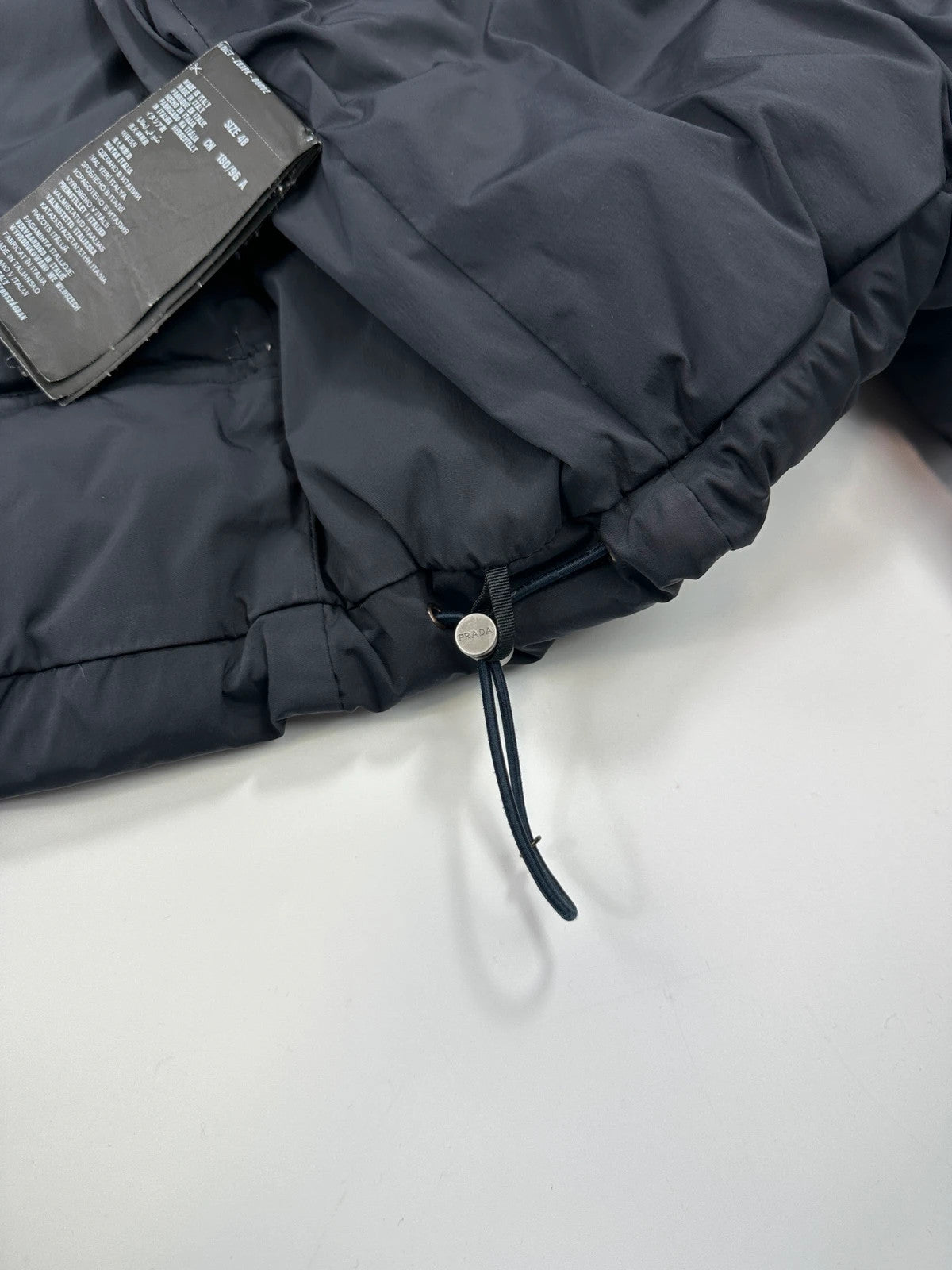 Prada dark navy hooded puffer jacket with triangle logo and vintage 2000s design.