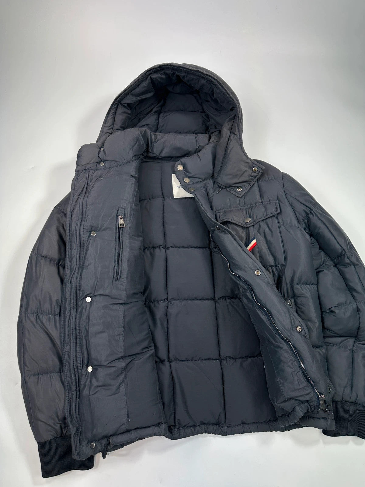 Moncler navy blue puffer jacket with French logo and hood, down-filled material.