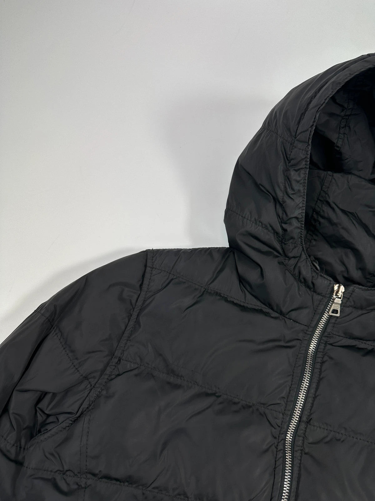 Prada black fitted nylon down puffer jacket with hood and logo detail.