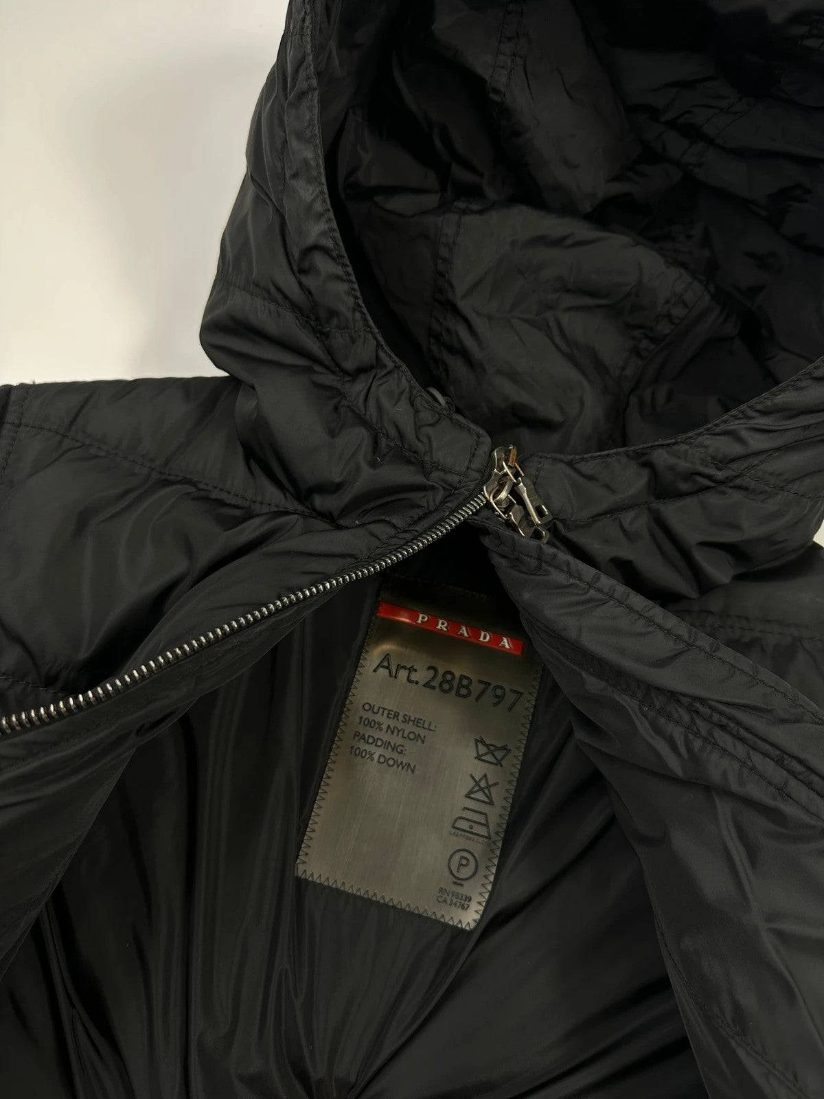 Prada black fitted nylon down puffer jacket with hood and logo detail.