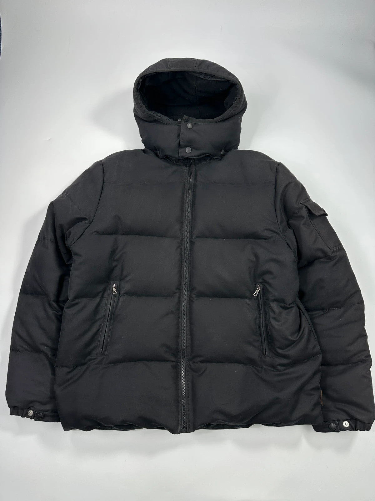 Moncler black hooded puffer jacket with logo patch and quilted down detailing.