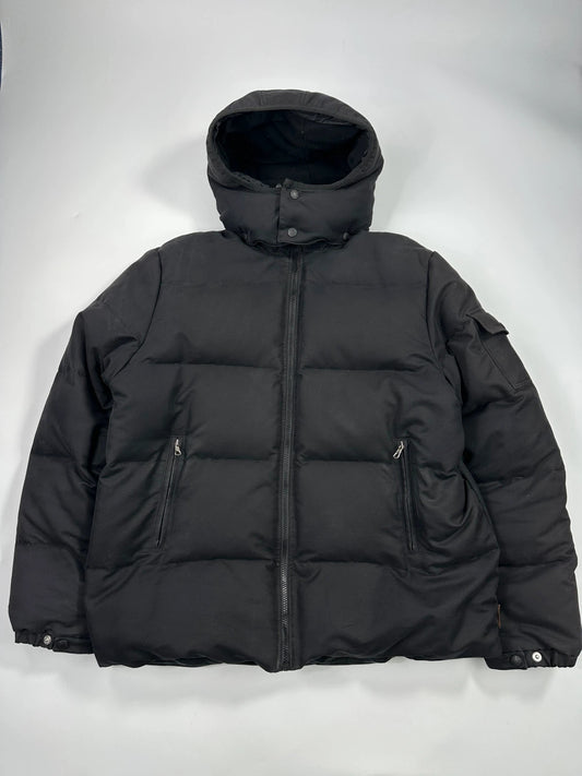 Moncler black hooded puffer jacket with logo patch and quilted down detailing.