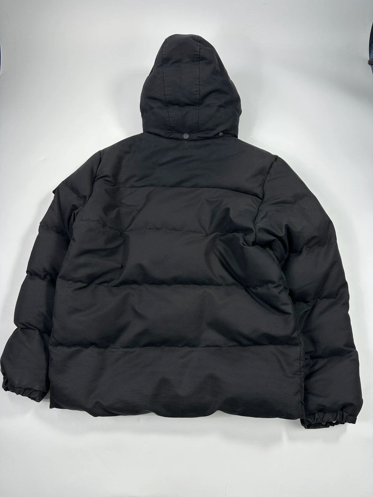 Moncler black hooded puffer jacket with logo patch and quilted down detailing.