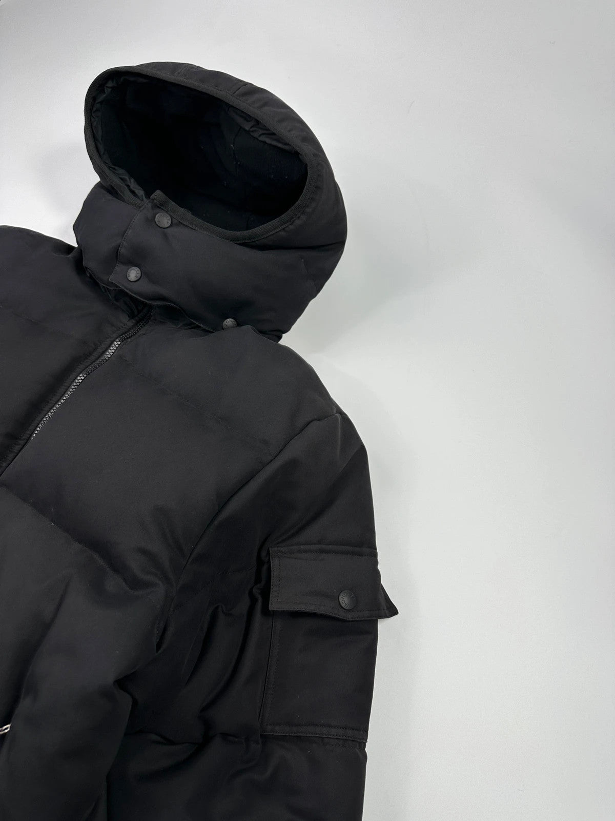 Moncler black hooded puffer jacket with logo patch and quilted down detailing.