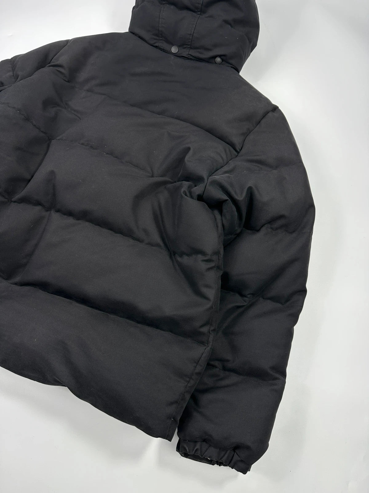 Moncler black hooded puffer jacket with logo patch and quilted down detailing.