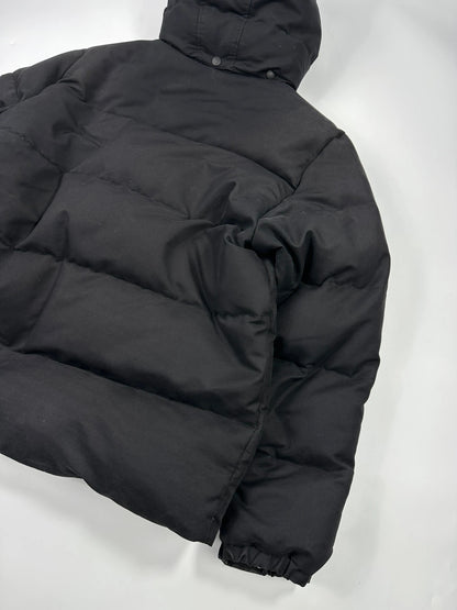 Moncler black hooded puffer jacket with logo patch and quilted down detailing.