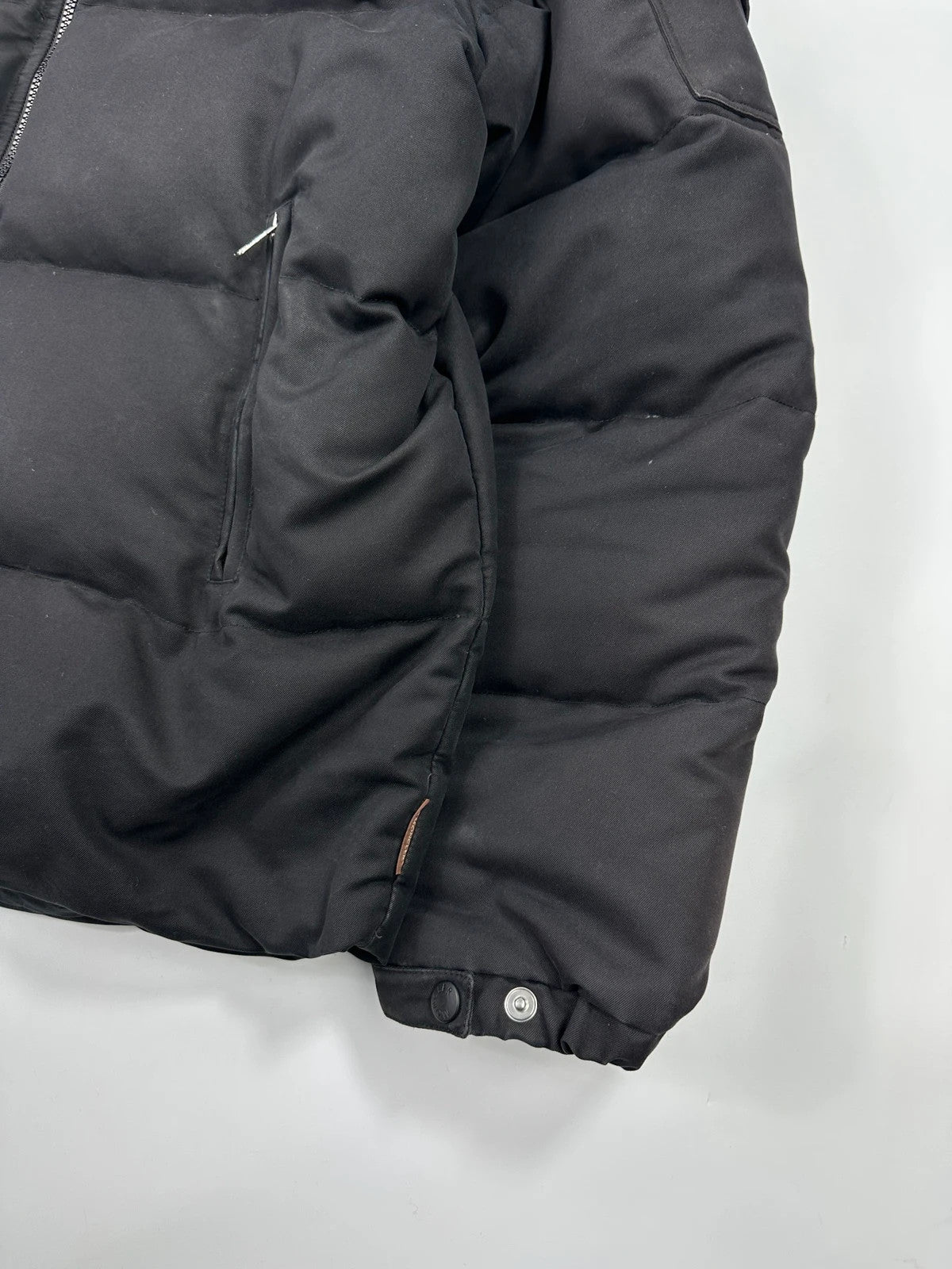 Moncler black hooded puffer jacket with logo patch and quilted down detailing.
