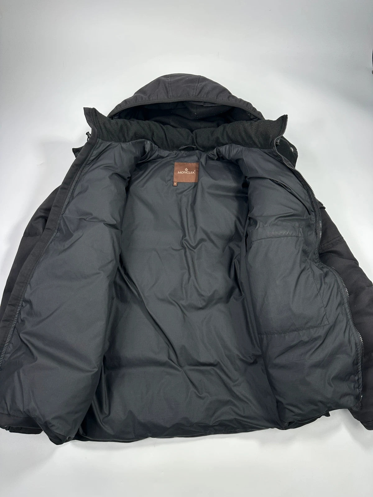 Moncler black hooded puffer jacket with logo patch and quilted down detailing.