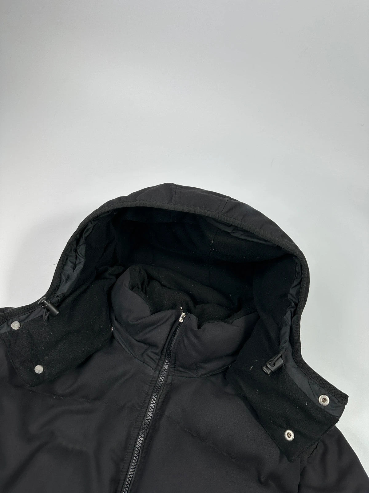Moncler black hooded puffer jacket with logo patch and quilted down detailing.