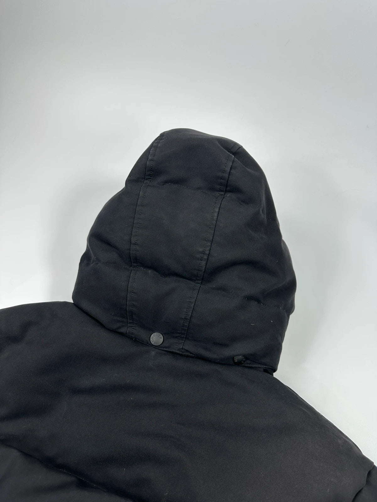 Moncler black hooded puffer jacket with logo patch and quilted down detailing.