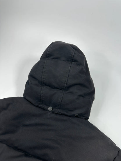 Moncler black hooded puffer jacket with logo patch and quilted down detailing.