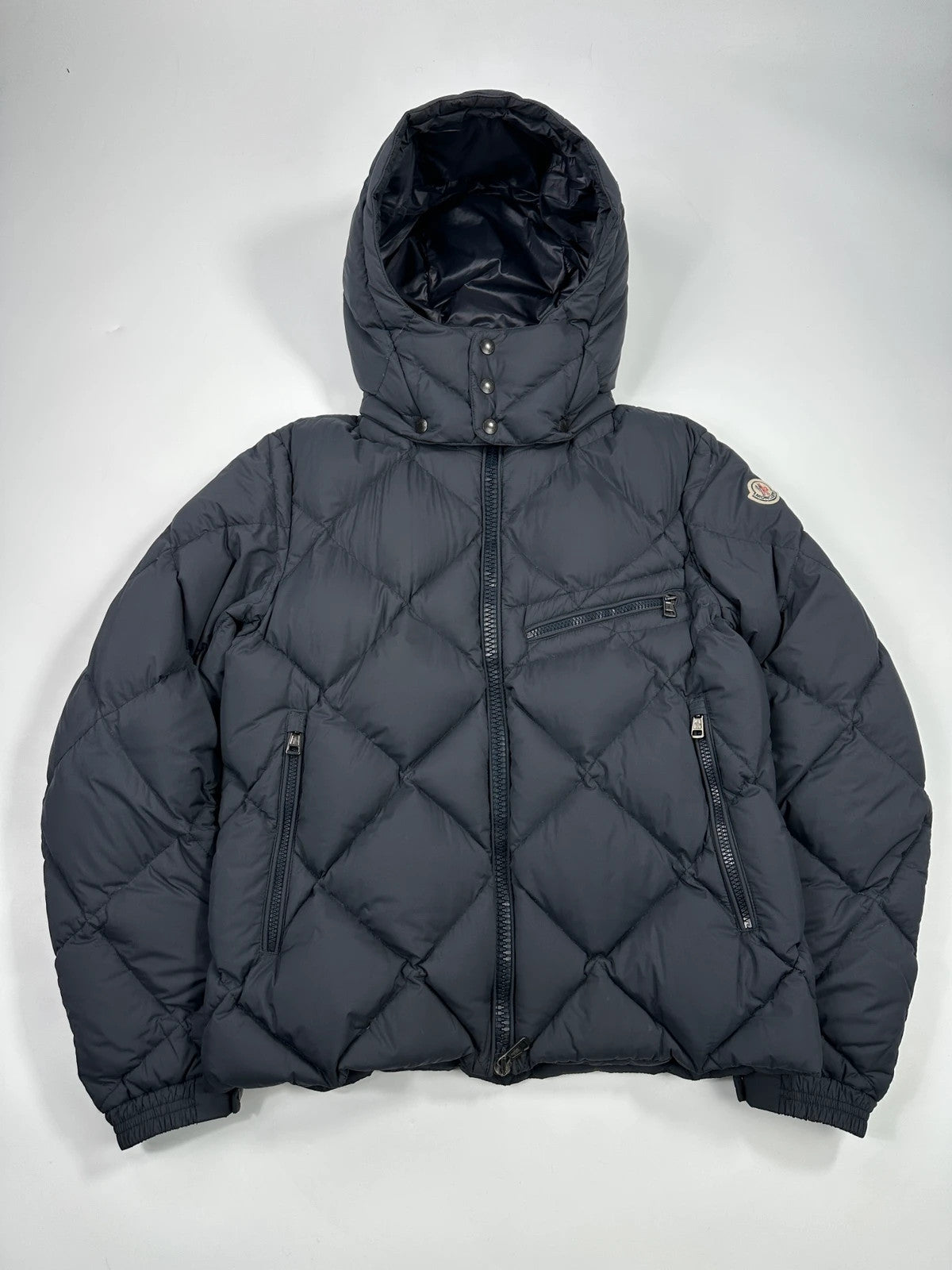 Moncler navy blue puffer jacket with diamond pattern, hood, and down filling.