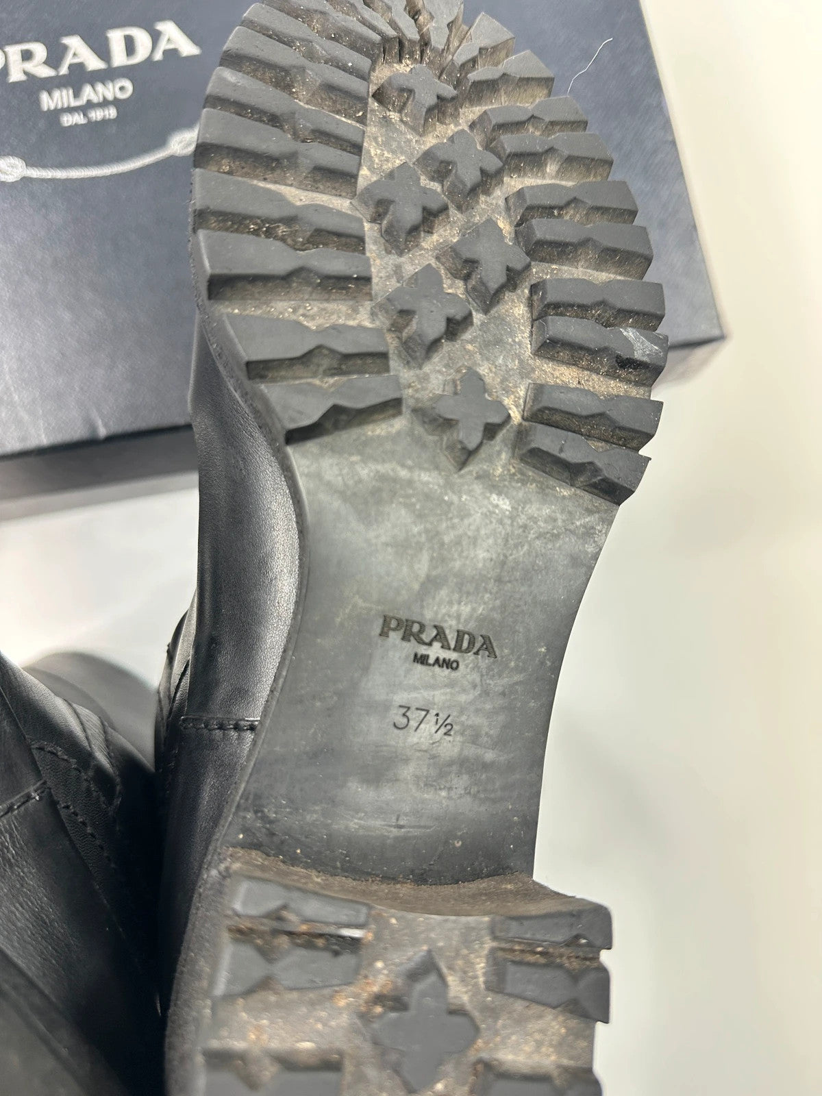 Prada black leather garter strap boots with minimalist design and original box.