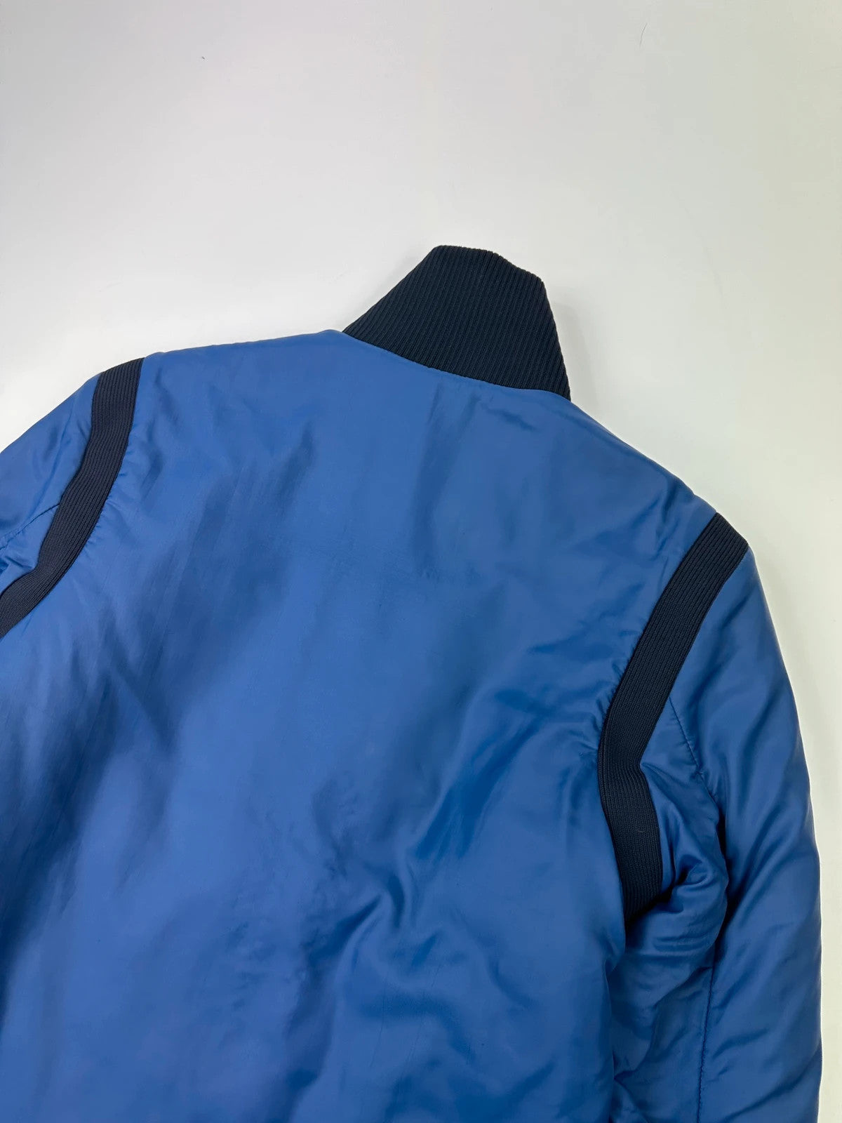 Prada blue padded nylon tech jacket with logo detail and minimalist design.