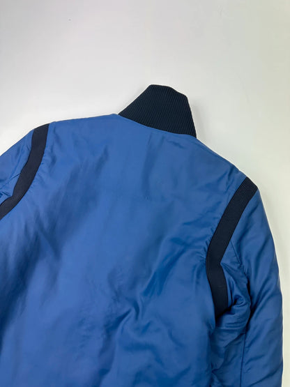 Prada blue padded nylon tech jacket with logo detail and minimalist design.