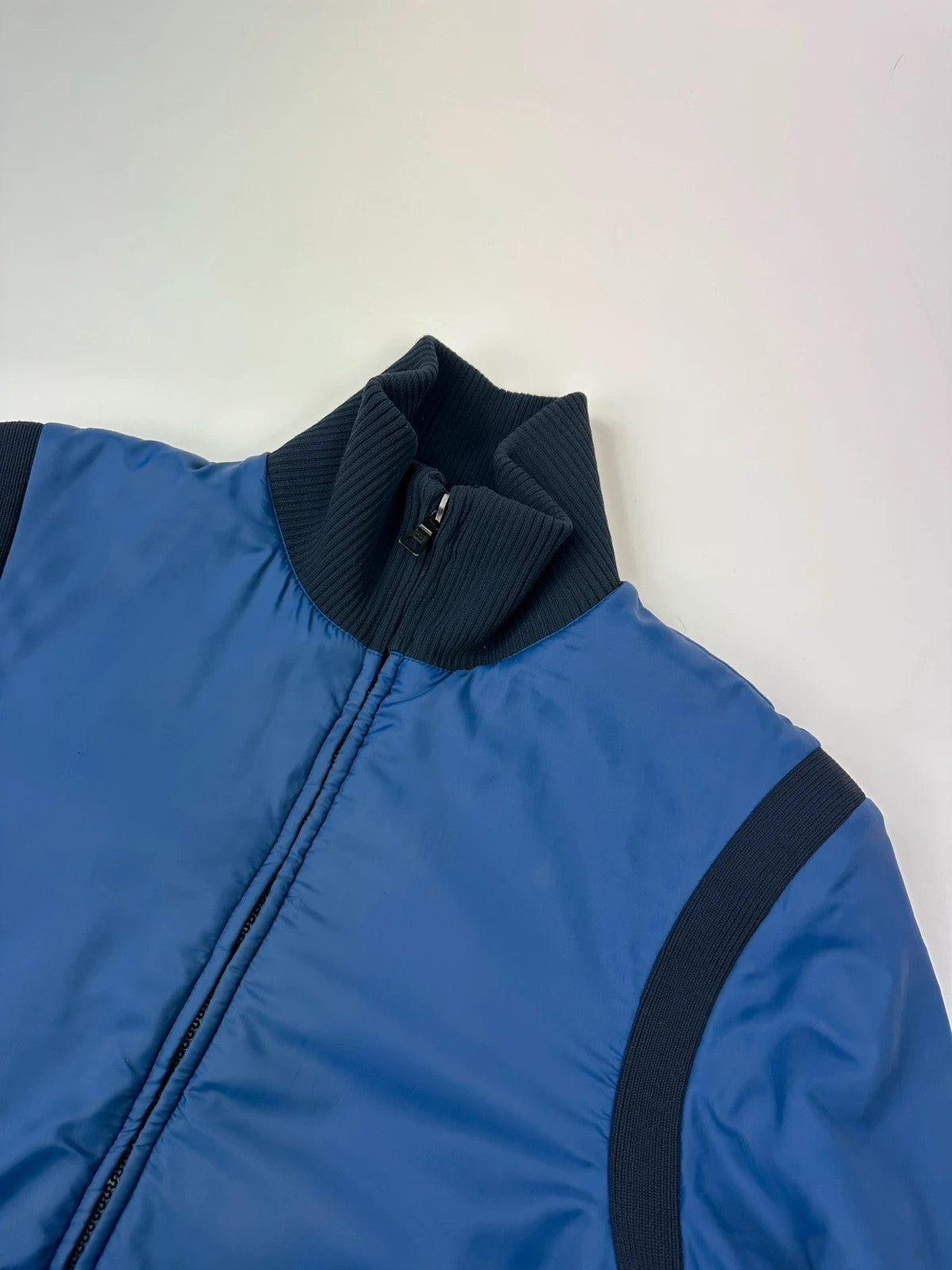 Prada blue padded nylon tech jacket with logo detail and minimalist design.
