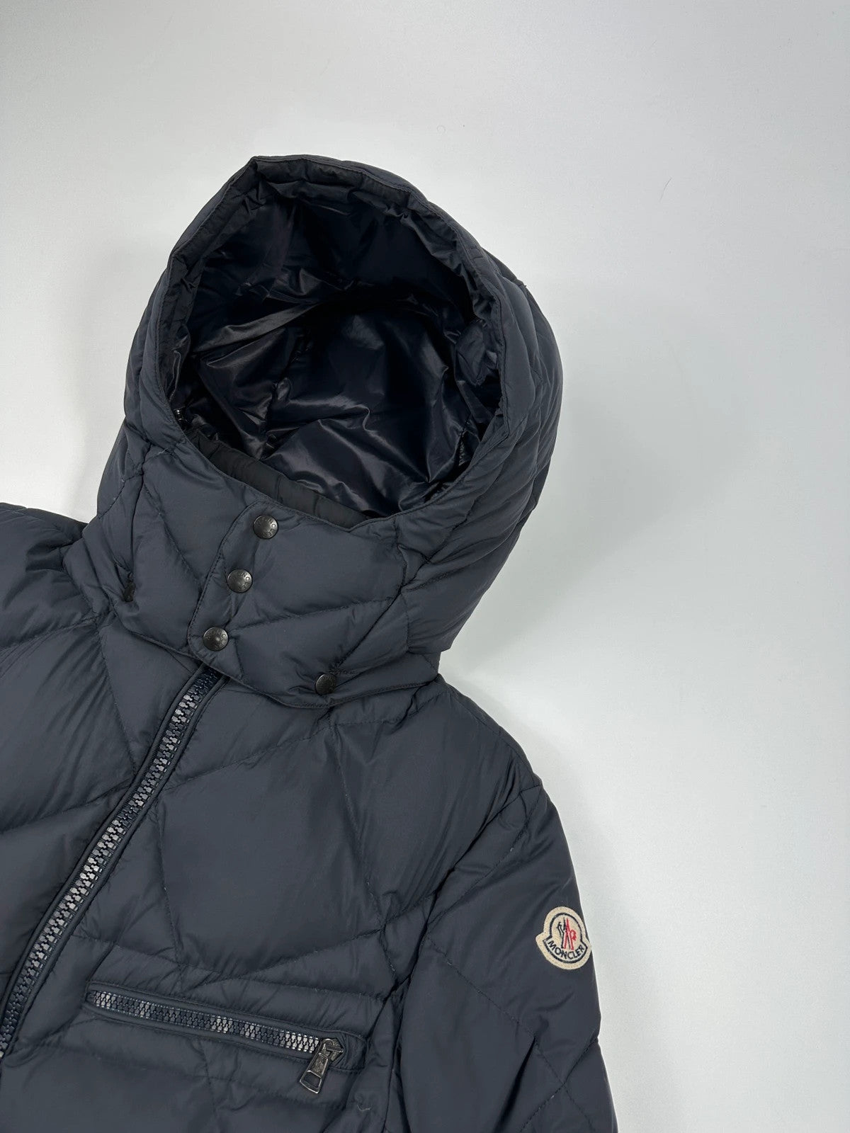 Moncler navy blue puffer jacket with diamond pattern, hood, and down filling.