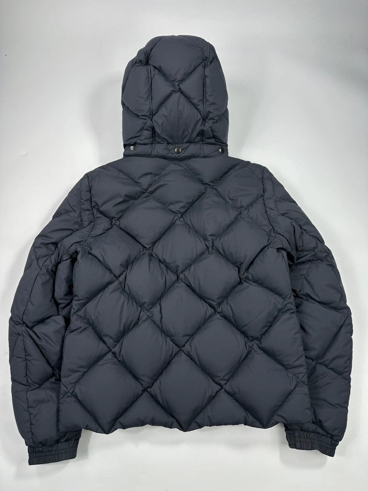 Moncler navy blue puffer jacket with diamond pattern, hood, and down filling.