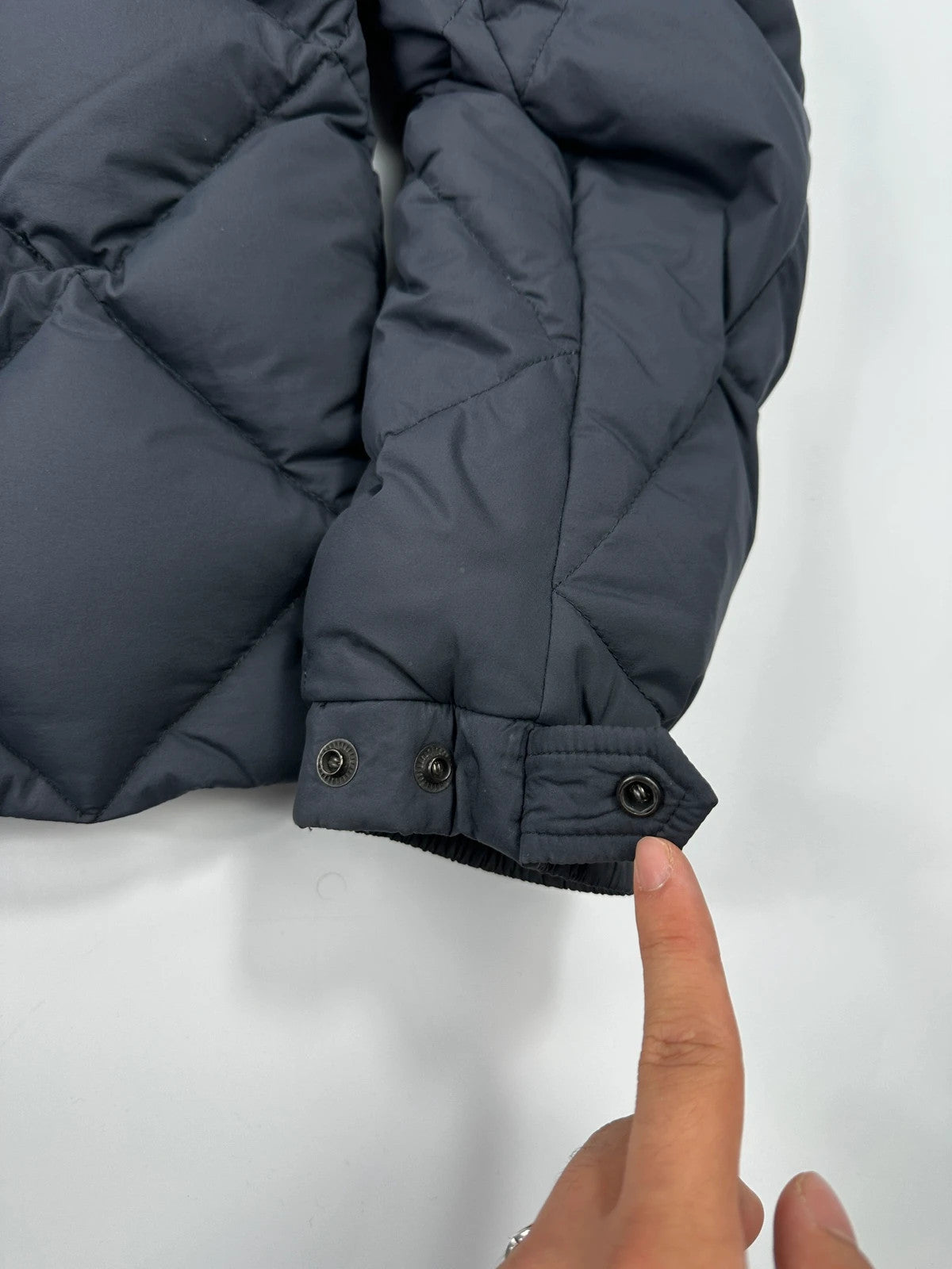 Moncler navy blue puffer jacket with diamond pattern, hood, and down filling.