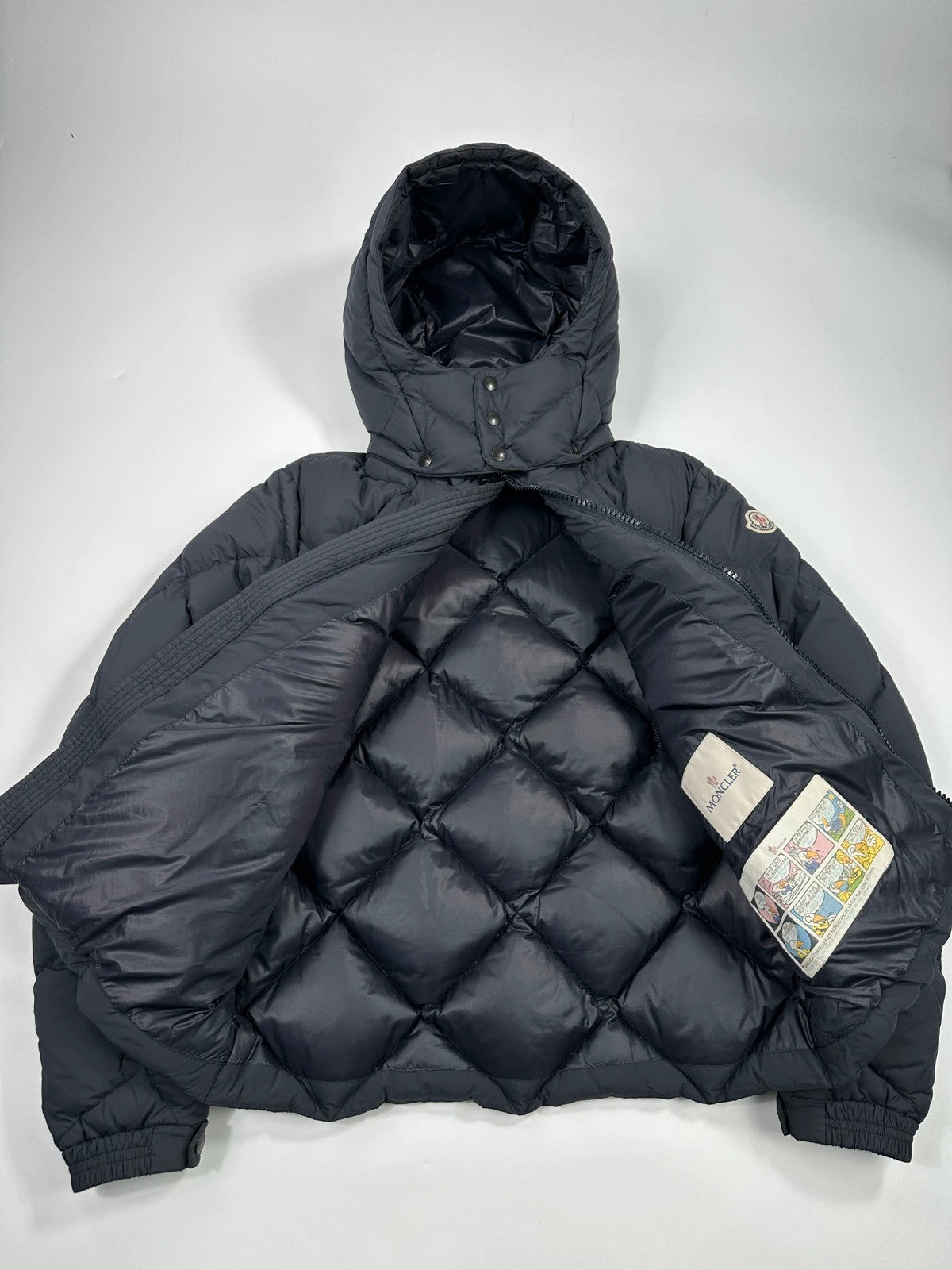 Moncler navy blue puffer jacket with diamond pattern, hood, and down filling.