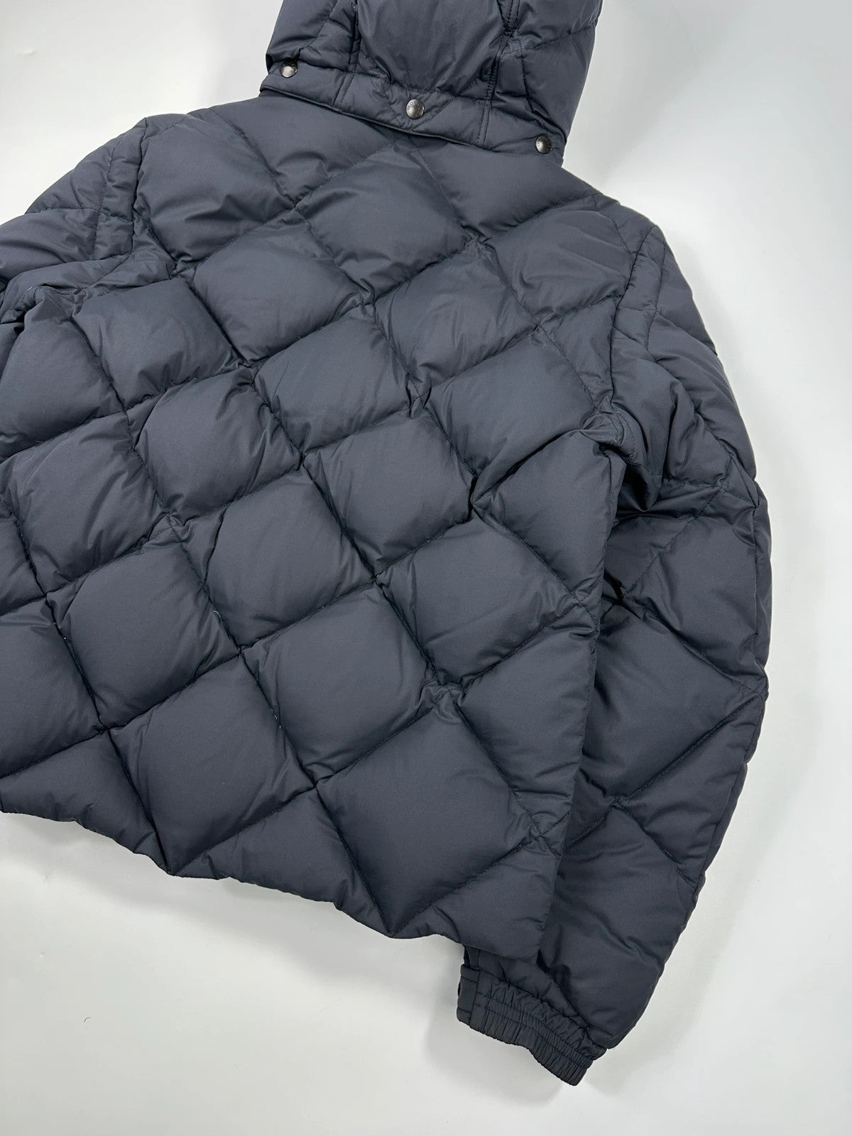 Moncler navy blue puffer jacket with diamond pattern, hood, and down filling.