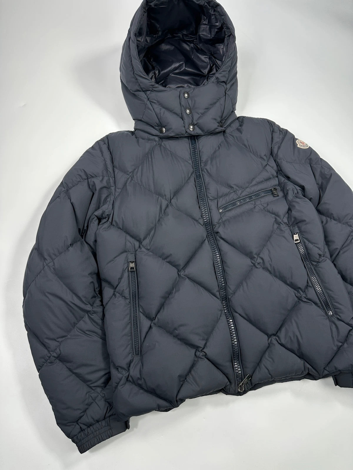 Moncler navy blue puffer jacket with diamond pattern, hood, and down filling.