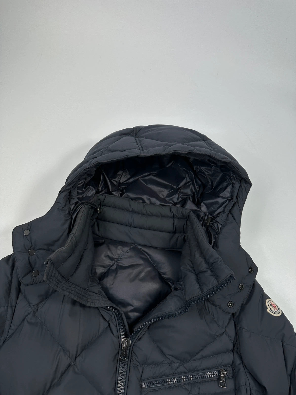 Moncler navy blue puffer jacket with diamond pattern, hood, and down filling.
