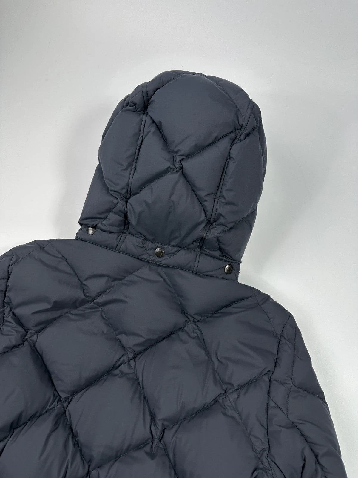Moncler navy blue puffer jacket with diamond pattern, hood, and down filling.