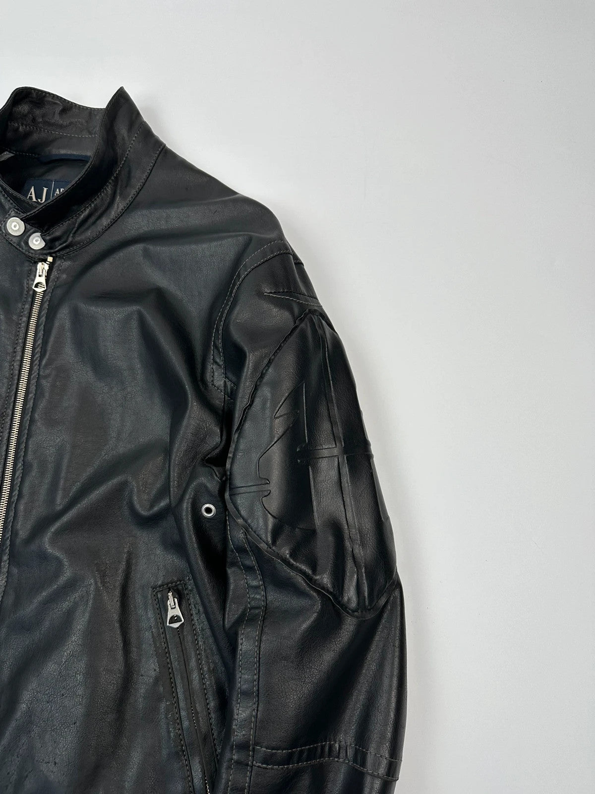 Armani Jeans black faux leather jacket with worn pockets and minimalist design.