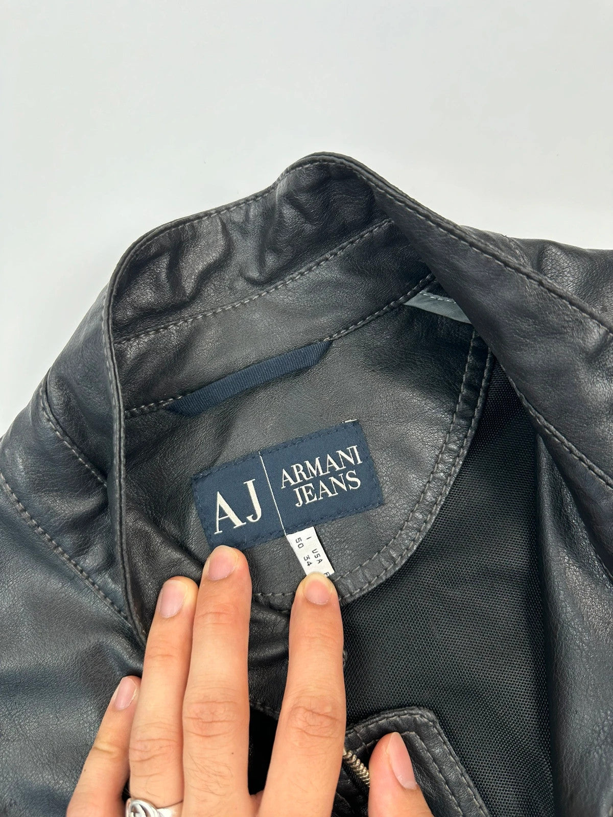 Armani Jeans black faux leather jacket with worn pockets and minimalist design.
