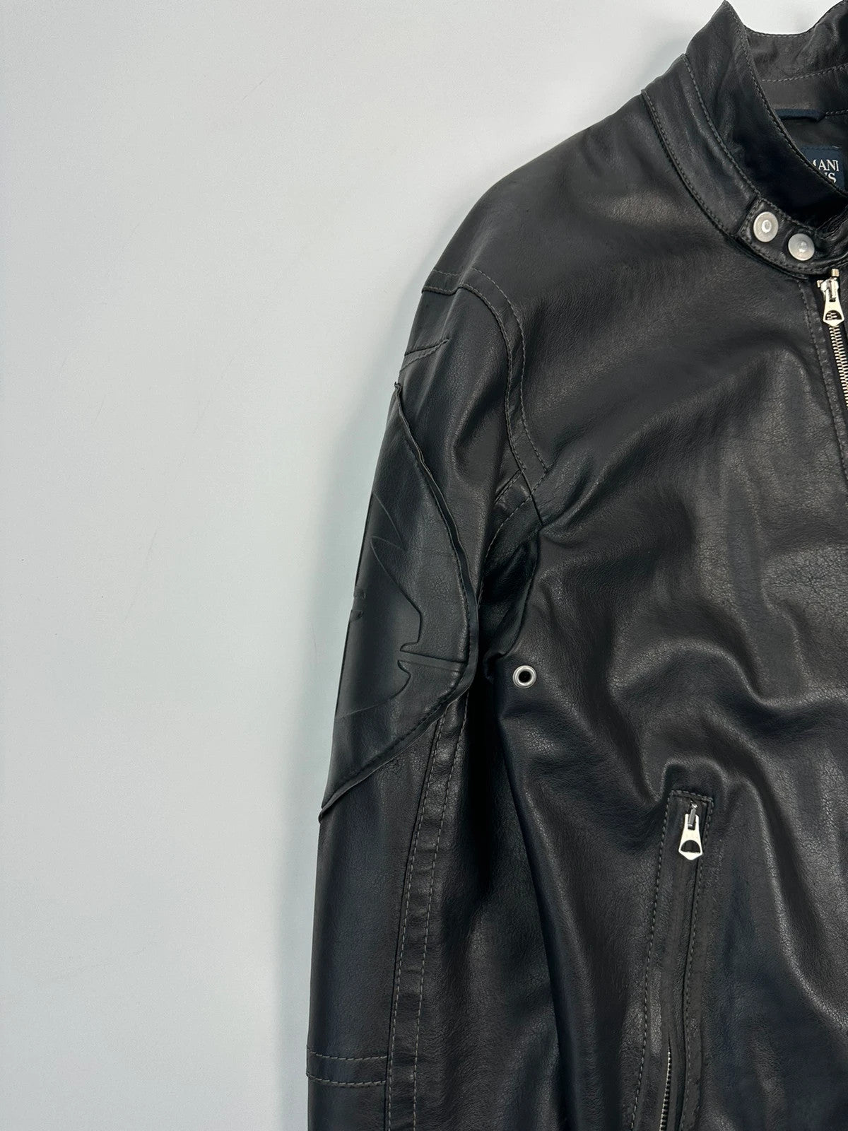Armani Jeans black faux leather jacket with worn pockets and minimalist design.