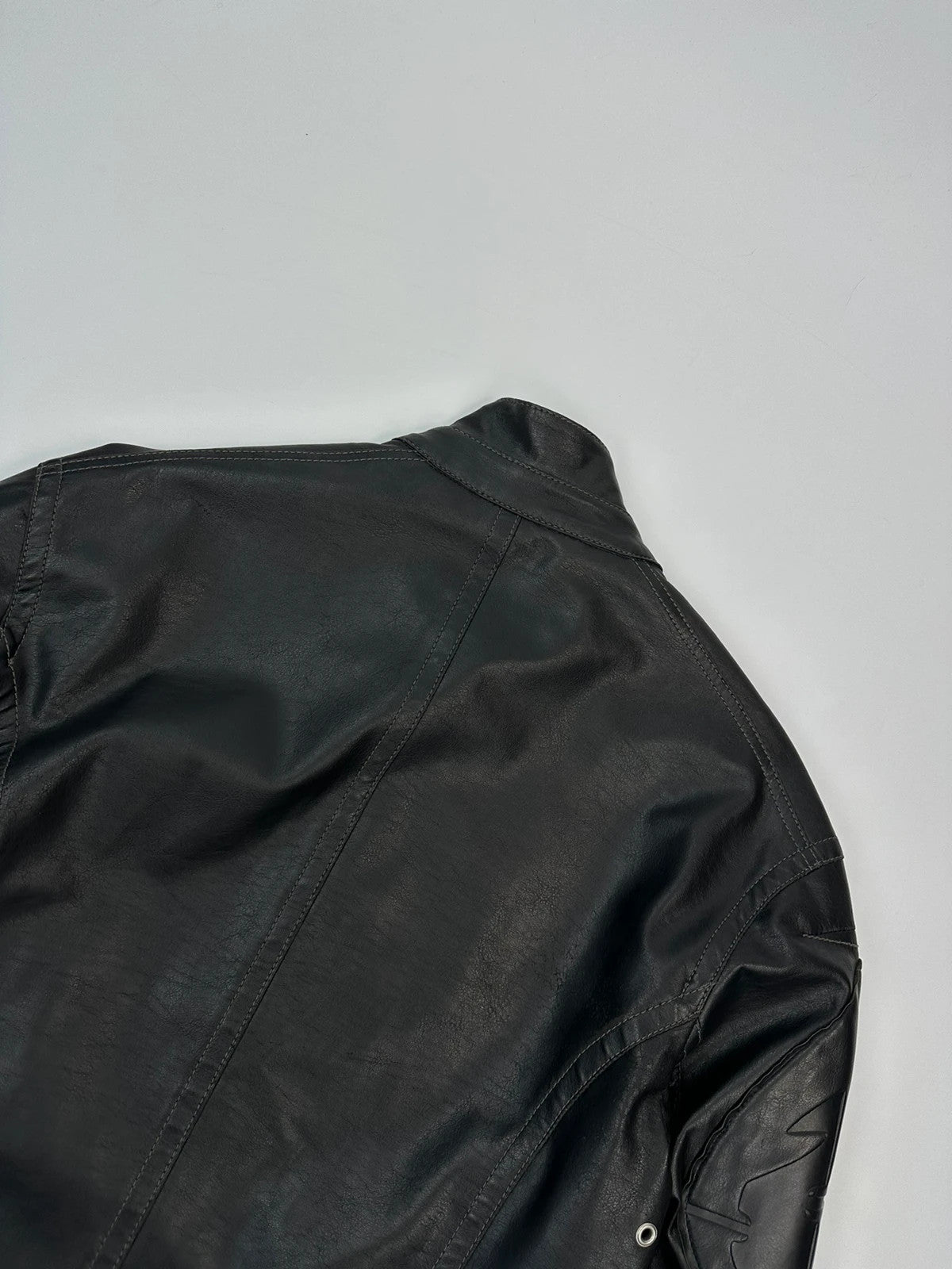 Armani Jeans black faux leather jacket with worn pockets and minimalist design.