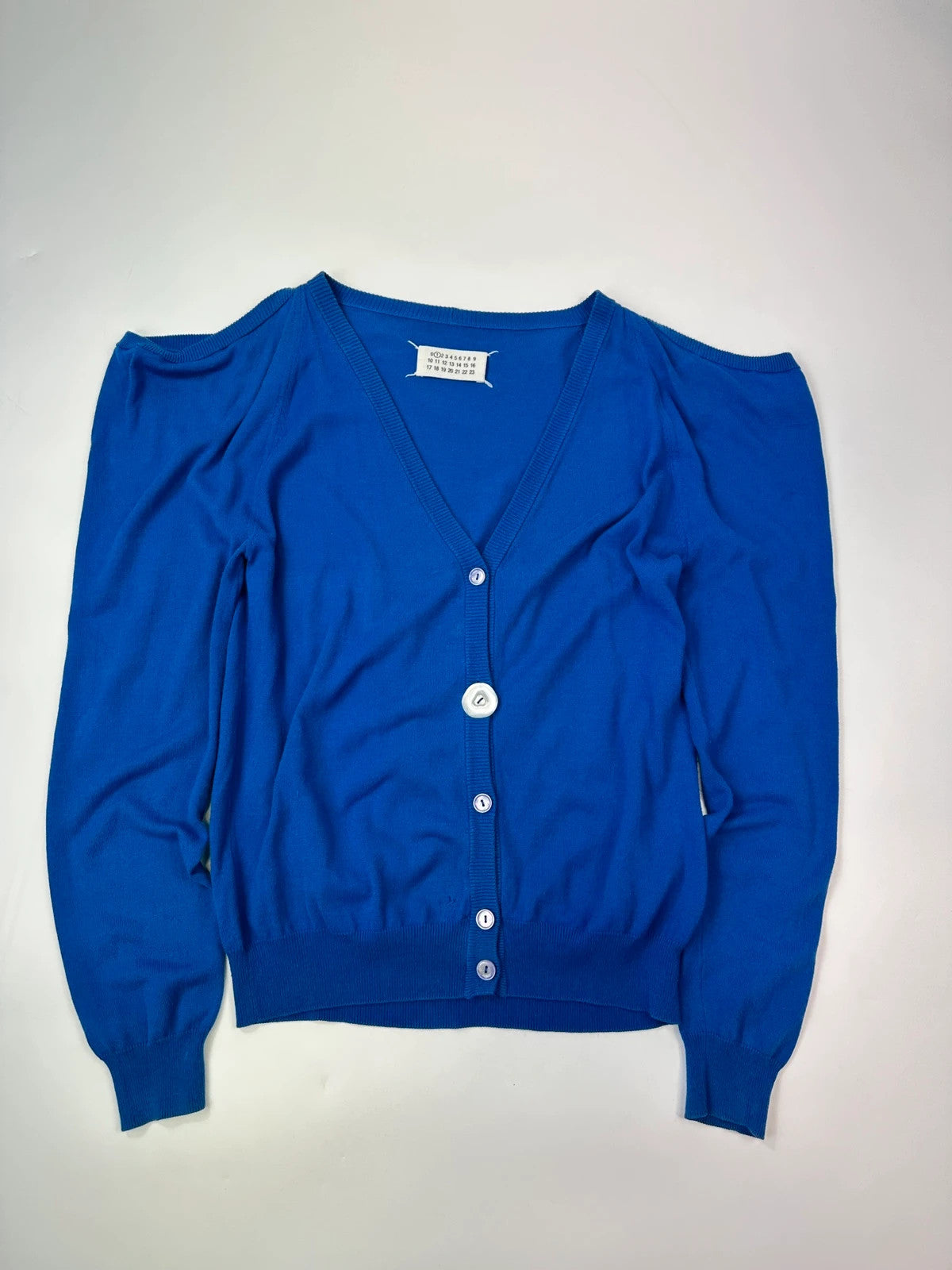 Maison Margiela electric blue cardigan with shoulder holes, minimalist design, soft knit material.