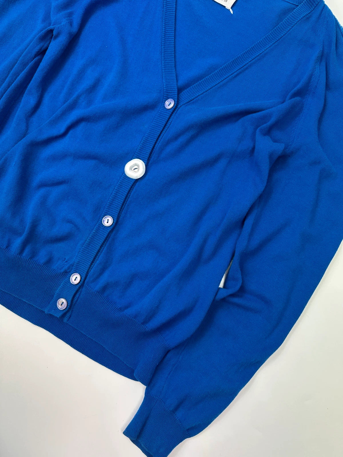 Maison Margiela electric blue cardigan with shoulder holes, minimalist design, soft knit material.
