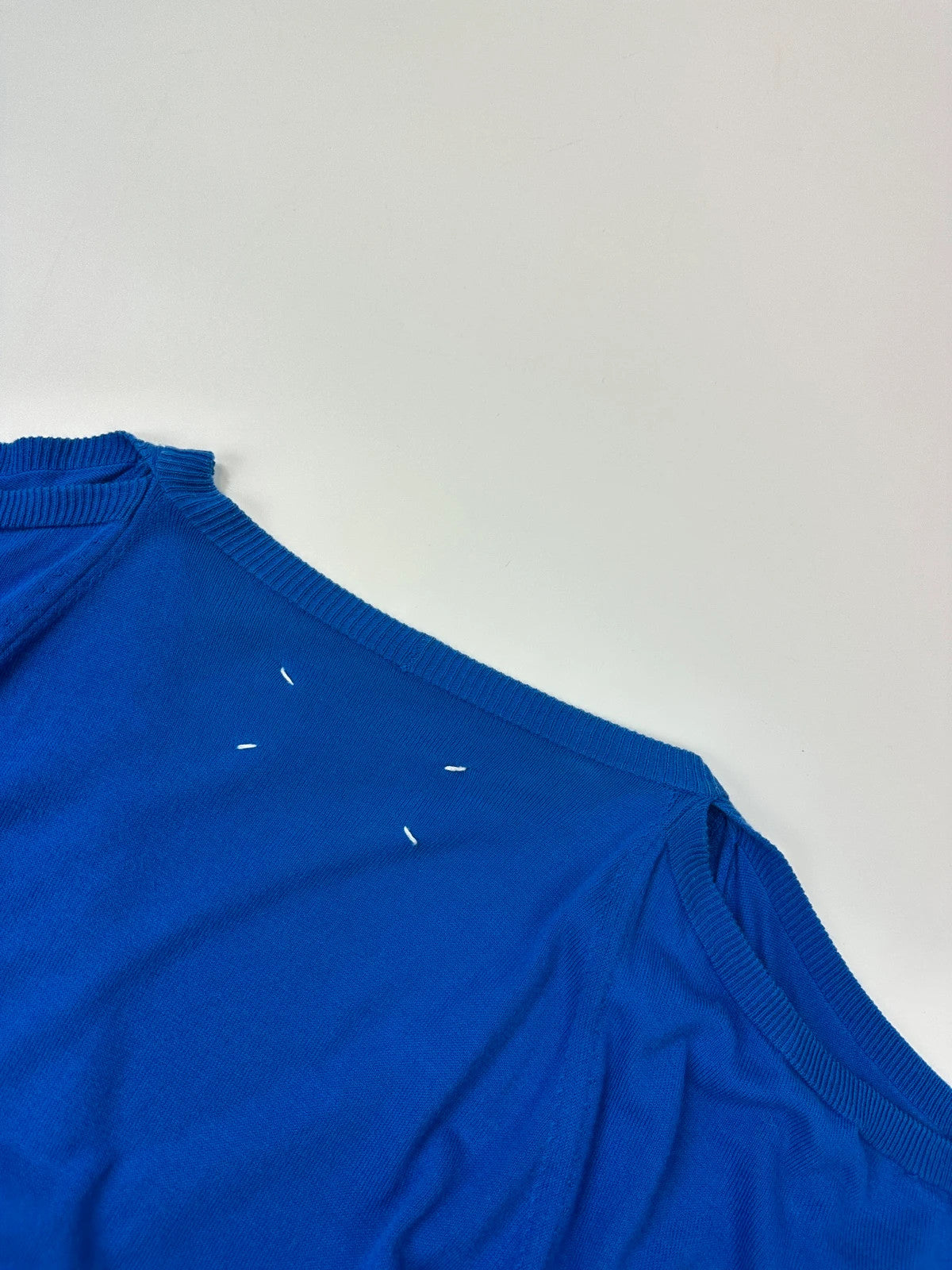 Maison Margiela electric blue cardigan with shoulder holes, minimalist design, soft knit material.