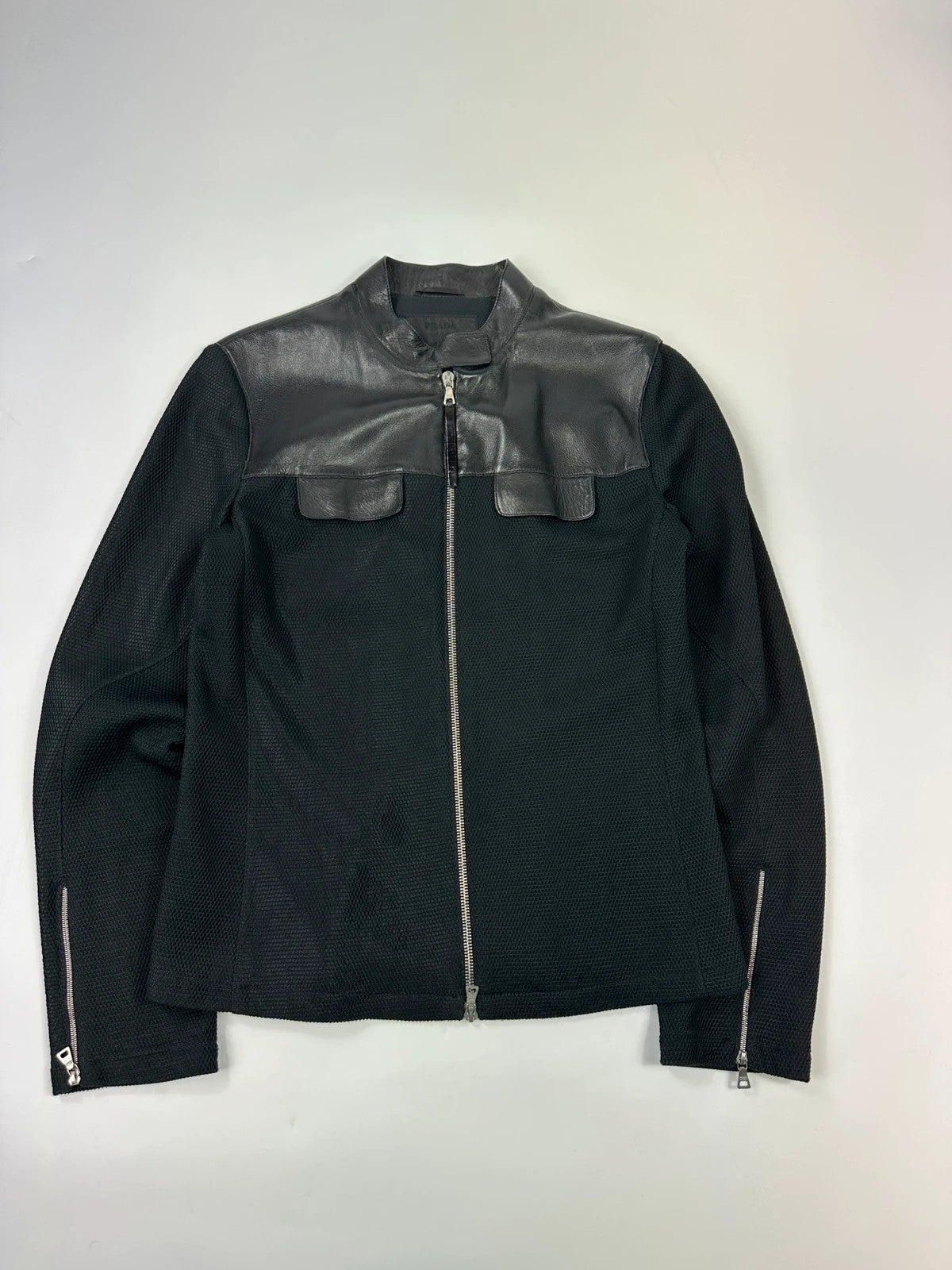 Prada black mesh and leather jacket with logo detailing and vintage design elements.