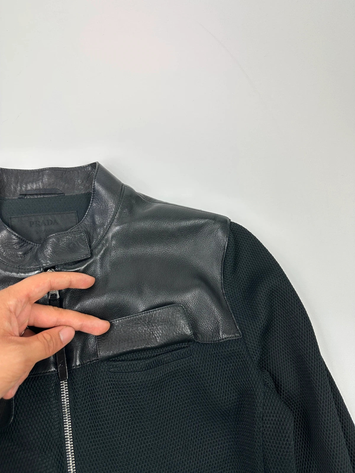 Prada black mesh and leather jacket with logo detailing and vintage design elements.