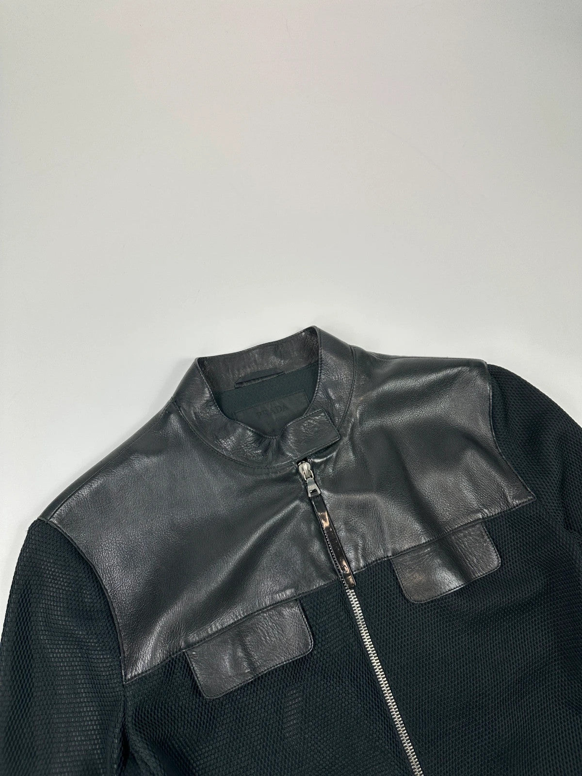 Prada black mesh and leather jacket with logo detailing and vintage design elements.