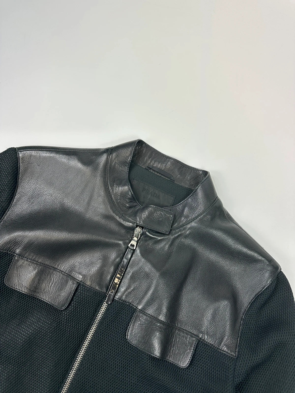 Prada black mesh and leather jacket with logo detailing and vintage design elements.