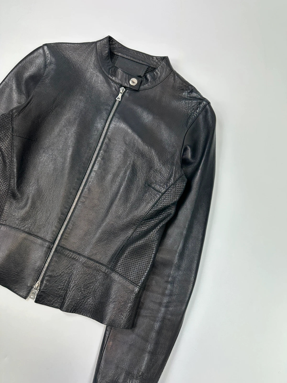 Prada black perforated leather jacket with subtle logo detailing and minimalist design.