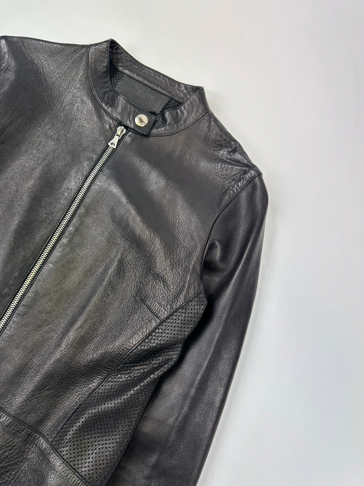Prada black perforated leather jacket with subtle logo detailing and minimalist design.