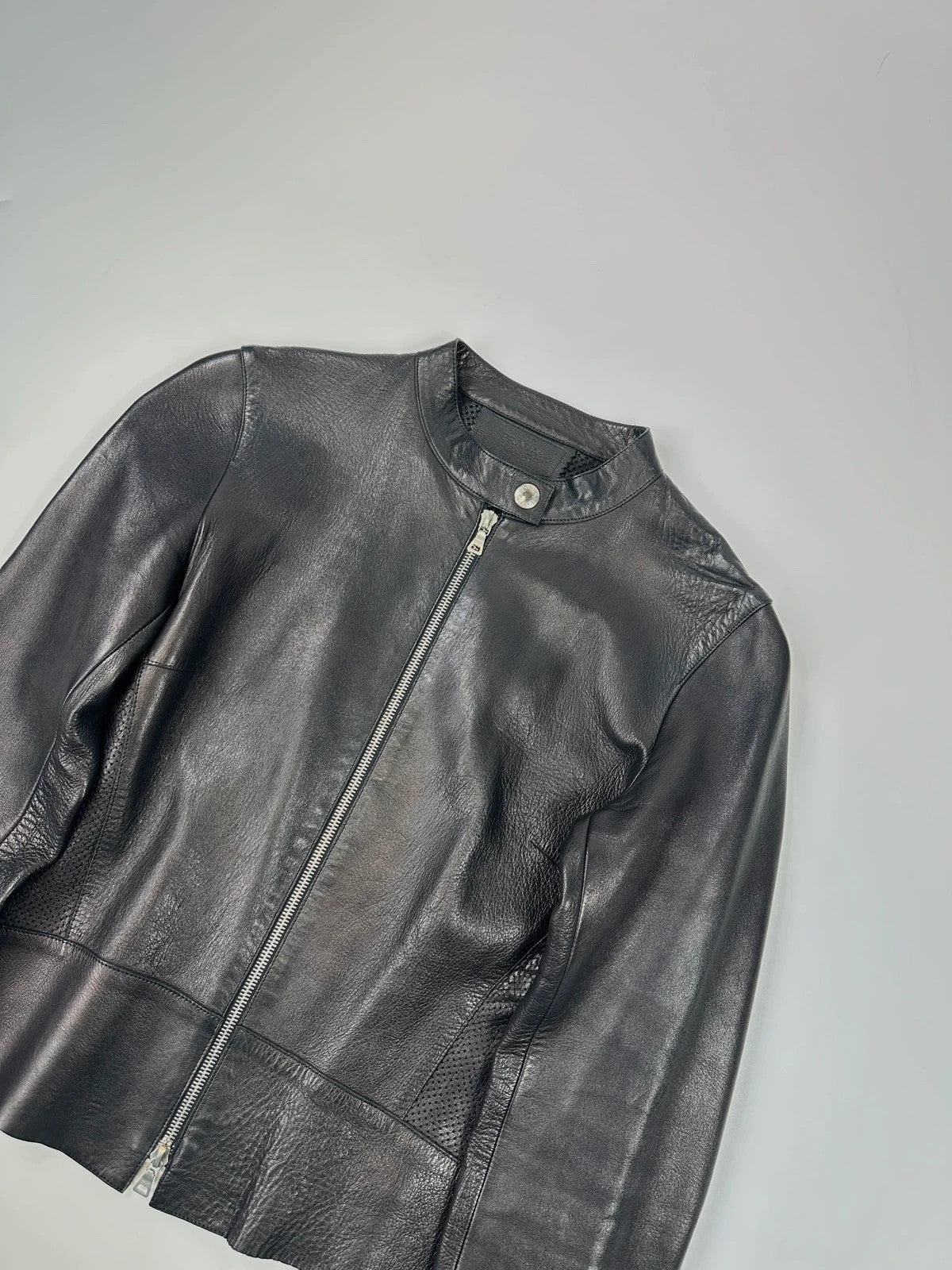 Prada black perforated leather jacket with subtle logo detailing and minimalist design.