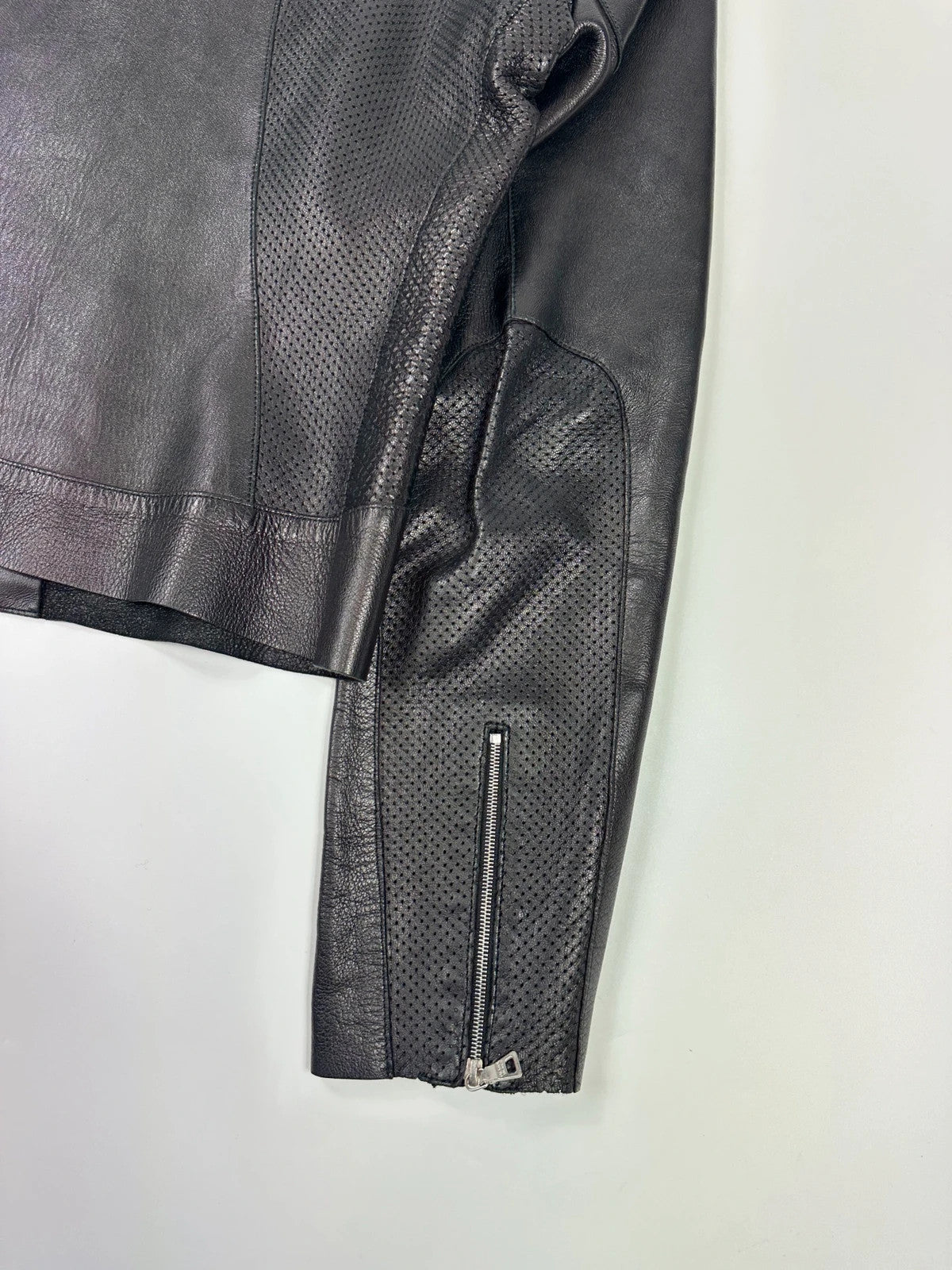 Prada black perforated leather jacket with subtle logo detailing and minimalist design.