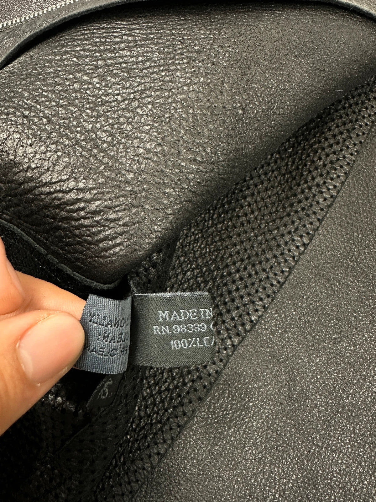 Prada black perforated leather jacket with subtle logo detailing and minimalist design.