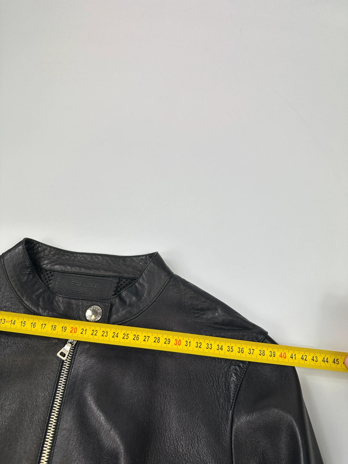 Prada black perforated leather jacket with subtle logo detailing and minimalist design.
