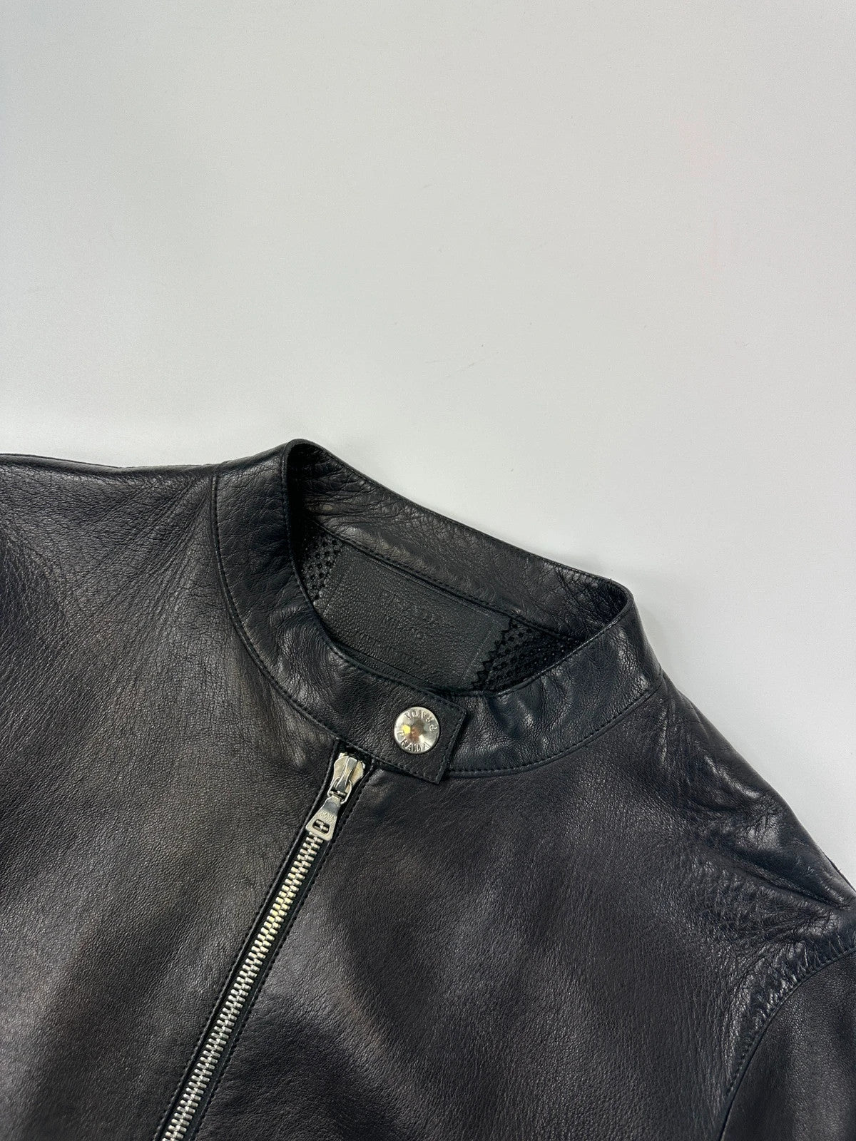 Prada black perforated leather jacket with subtle logo detailing and minimalist design.