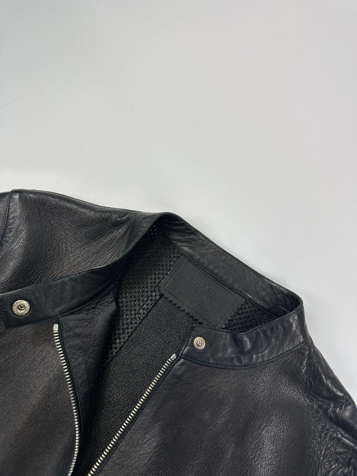 Prada black perforated leather jacket with subtle logo detailing and minimalist design.