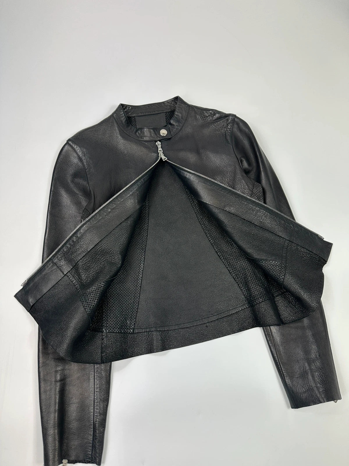 Prada black perforated leather jacket with subtle logo detailing and minimalist design.