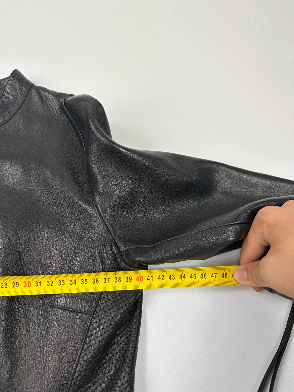 Prada black perforated leather jacket with subtle logo detailing and minimalist design.
