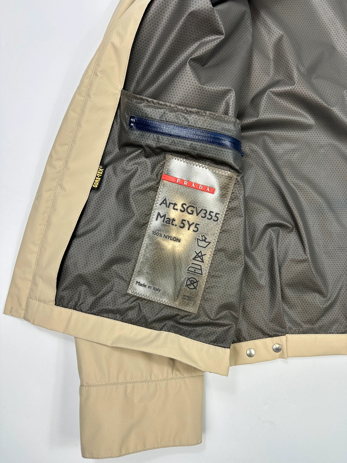 Prada beige Gore-Tex jacket packable into pocket, features logo and nylon material.